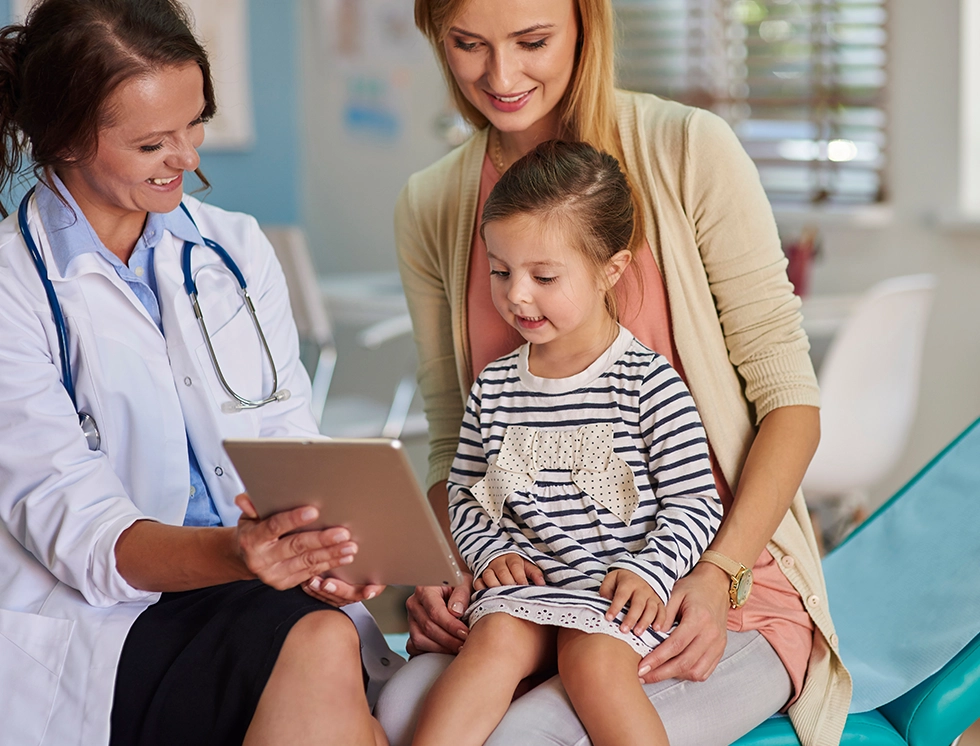 A caring doctor engages with a young patient and her mother